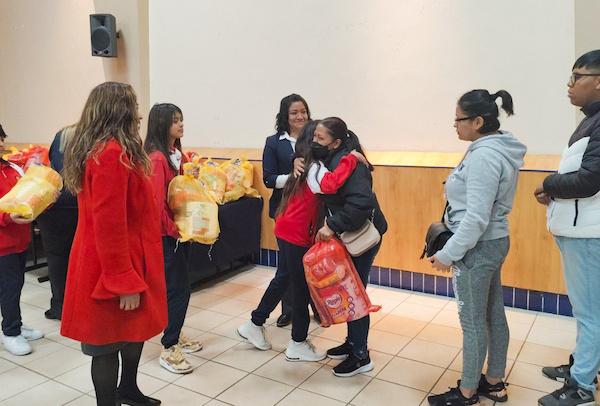 maestra con alumnos obsequiando despensa