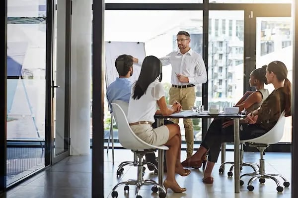 contadores y financieros en oficina viendo un pizarron