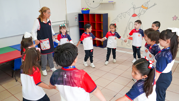 alumnos en salon de clases tomados de la mano en circulo